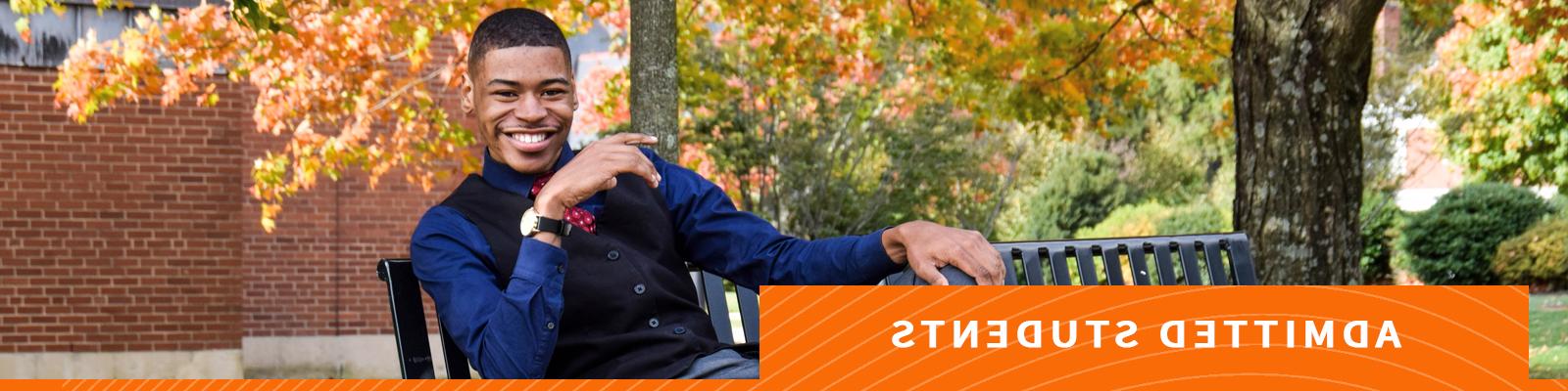 Man smiling on bench on campus